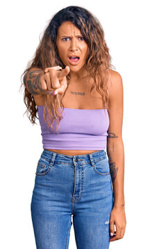 Young hispanic woman with tattoo wearing casual clothes pointing displeased and frustrated to the camera, angry and furious with you