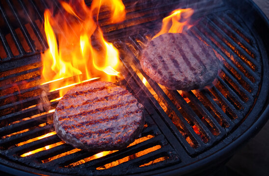 Barbecue wagyu beef Hamburger grilled as close-up on a charcoal grill with fire and smoke