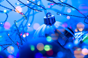 Christmas and New Year blue color baubles decoration background with colourful lights of garlands. Art design with holiday ball. Beautiful Christmas balls closeup. Xmas backdrop 