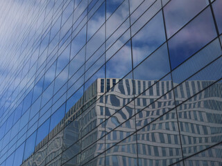 reflection of an office building and a cloudy sky in a glass facade