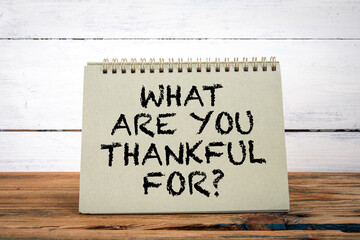 What Are You Thankful For. Green notepad on wooden texture table and white background
