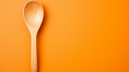 Well-used wooden spatula and spoon on a bright orange backdrop.