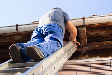 bricklayer construction worker on metalic staircase to repair old tile roof