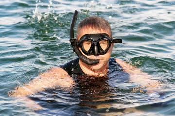 Fototapeta premium man practicing snorkeling sport in calm sea looking fishes