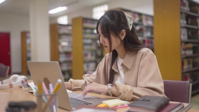 young asian student woman doing lesson exam at college library.