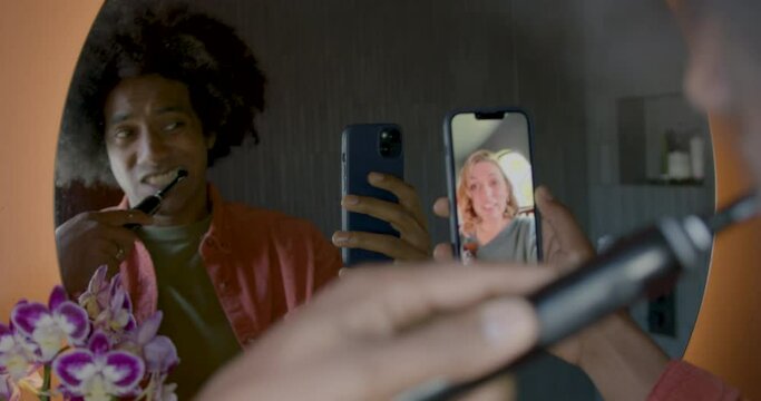 Male Brushing Teeth and talking to Girlfriend on Smart phone in Bathroom