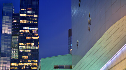 The glass facades of a modern skyscrapers at night. Modern glass office in city. Big glowing windows in modern offices buildings at night. In rows of windows light shines.