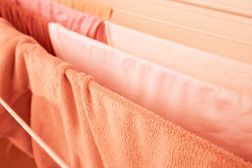 clothes peach fuzz Color year 2024 hanging on dryer, delicate satin with soft pleats, concept Color...
