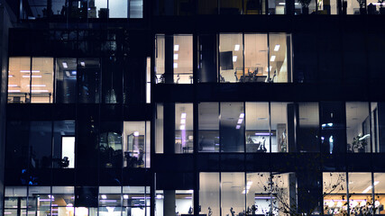 Fragment of the glass facade of a modern corporate building at night. Modern glass office  in city.  - obrazy, fototapety, plakaty