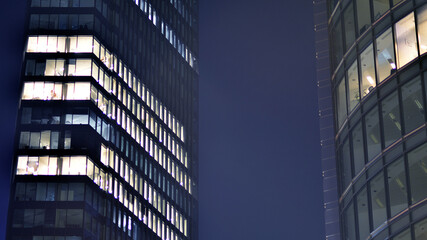 The glass facades of a modern skyscrapers at night. Modern glass office in city. Big glowing...