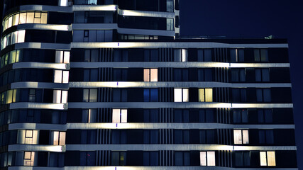 Glowing windows of the multi-storey building in night. View of modern residential building in...