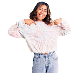 Young beautiful mixed race woman wearing casual tie dye sweatshirt looking confident with smile on...