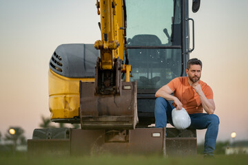 Worker with bulldozer on site construction. Man excavator worker. Construction driver worker with excavator on the background. Construction worker with tractor or construction vehicle at building.