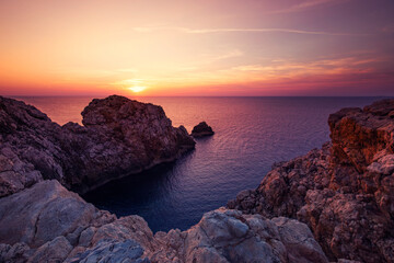 Krajobraz morski, różowy zachód słońca, skaliste wybrzeże wyspy Minorka (Menorca), Hiszpania	