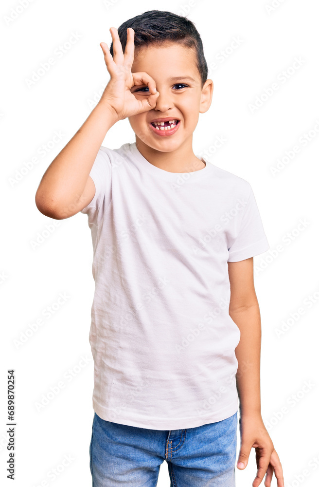 Wall mural Little cute boy kid wearing casual white tshirt smiling happy doing ok sign with hand on eye looking through fingers