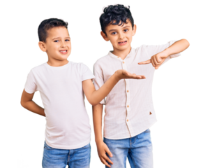 Couple of little brothers together wearing casual clothes amazed and smiling to the camera while presenting with hand and pointing with finger.
