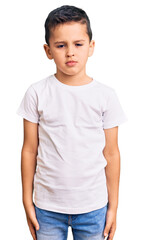 Little cute boy kid wearing casual white tshirt with serious expression on face. simple and natural looking at the camera.