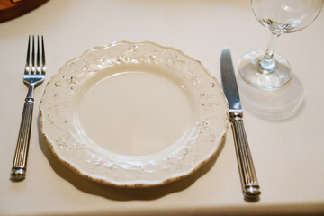 Top view. White plate in retro style with cutlery and glass.