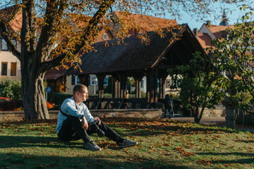 Professional Photographer Taking Picture Of Beautiful Autumn Park. Man Professional Photographer Sit With Camera And With Smartphone In Autumn Park. Retouched, Vibrant Colors, Brownish Tones.