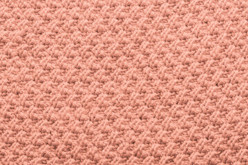 Trendy color of 2024 Year Peach Fuzz. Knit texture of wool knitted fabric with pattern background. Place for text. close up of abstract fabric texture