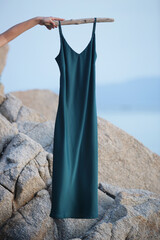 Green silk maxi camisole dress flying on the soft breeze on the beach