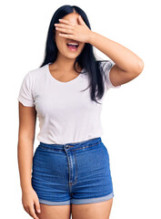 Young beautiful asian girl wearing casual clothes and glasses smiling and laughing with hand on face covering eyes for surprise. blind concept.