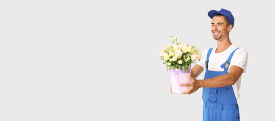 Delivery man holding bouquet of flowers on light background with space for text