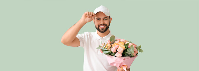 Delivery man holding bouquet of flowers on green background