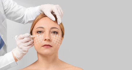 Mature woman receiving filler injection in face against grey background with space for text. Skin care concept