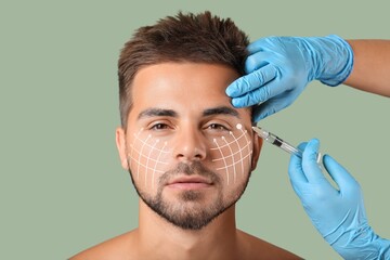 Handsome man receiving filler injection on green background. Skin care concept