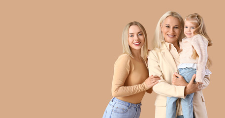 Cute little girl with her mother and granny on beige background with space for text