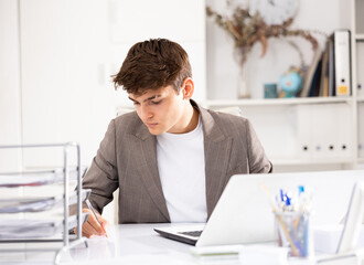 Man office manager sitting at table and using laptop computer