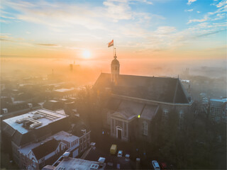 Drone view across town of Sneek with Dutch flag on top of a church at sunrise