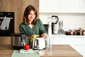 Young woman cleaning electric toaster in light kitchen