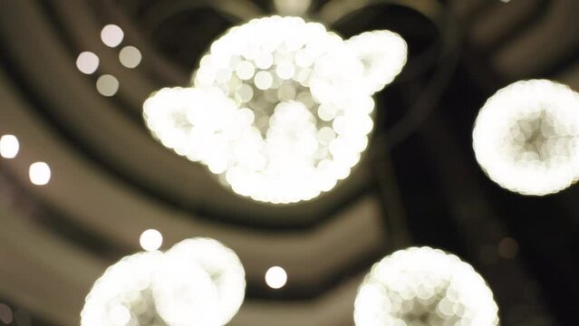 Chandeliers Hanging from the Ceiling of a High-ceilinged Space, Shaped like Spheres, Image in Defocus.