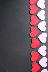 Red and pink hearts on a black dark background with space for text. Copy Space Valentine's Day. Festive background