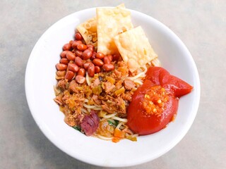 mie ayam. chicken noodle. spiced noodles topped with chopped chicken cooked with spices, peanuts, fried dumplings and bok choy vegetables. savory traditional food
