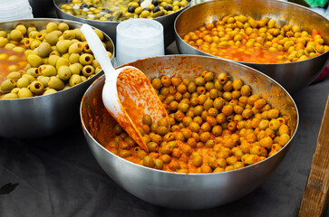 Containers filled with pitted green Spanish olives marinated in spices