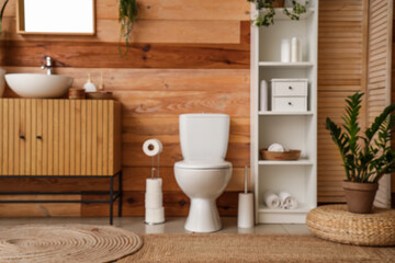 Interior of modern restroom with toilet bowl, wooden cabinet and shelving unit