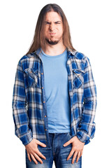 Young adult man with long hair wearing casual shirt puffing cheeks with funny face. mouth inflated with air, crazy expression.