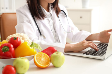 Female nutritionist working with laptop at table in office, closeup
