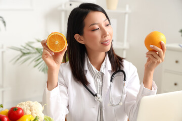 Female Asian nutritionist with oranges in office