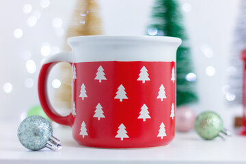 close up large red cup with pattern of white Christmas trees on table with Christmas decorations. celebration, holiday
