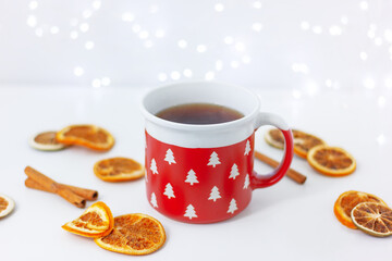 red cup with fir trees and dried lemon and cinnamon on table