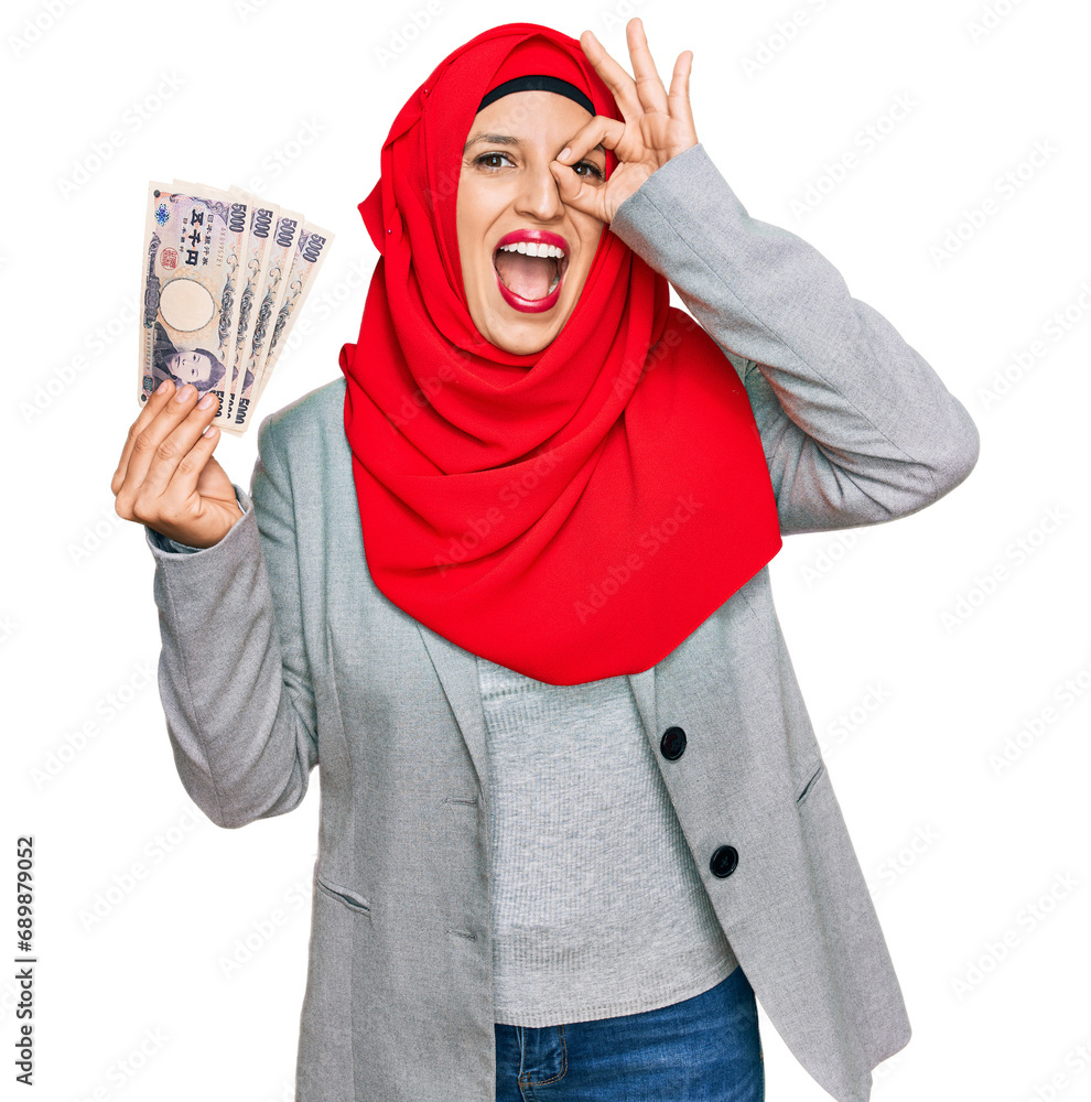 Sticker Beautiful hispanic woman wearing islamic hijab holding japanese yen banknotes smiling happy doing ok sign with hand on eye looking through fingers