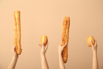 Female hands holding loaves of different fresh bread on beige background
