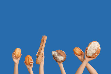Female hands holding loaves of different fresh bread on blue background
