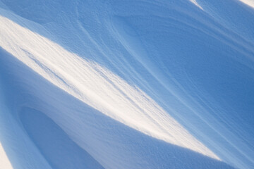 Snow texture. Wind sculpted patterns on snow surface. Wind in the tundra and in the mountains on the surface of the snow sculpts patterns and ridges (sastrugi). Arctic, Polar region. Winter background