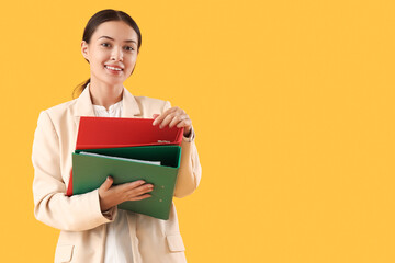 Young Asian businesswoman with document folders on yellow background