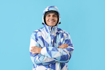Frozen young man in winter clothes on color background